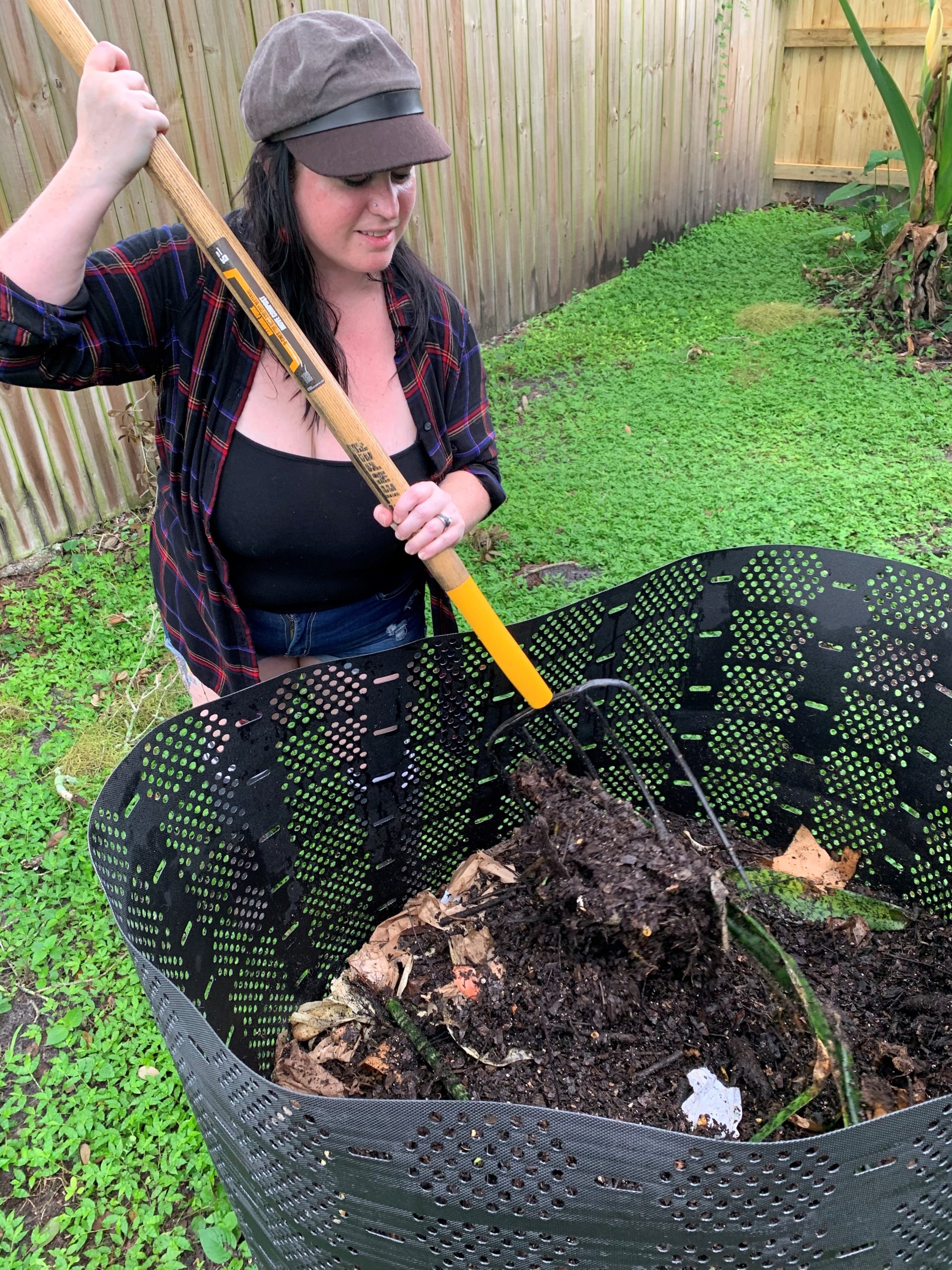 woman raking organic material in a geobin compost bin