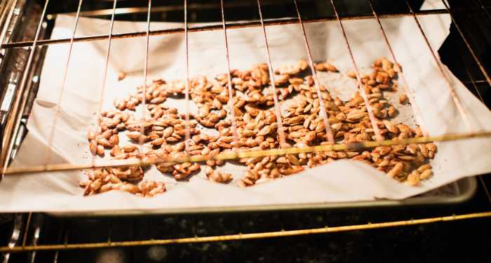 pumpkin seeds roasting on pan in oven