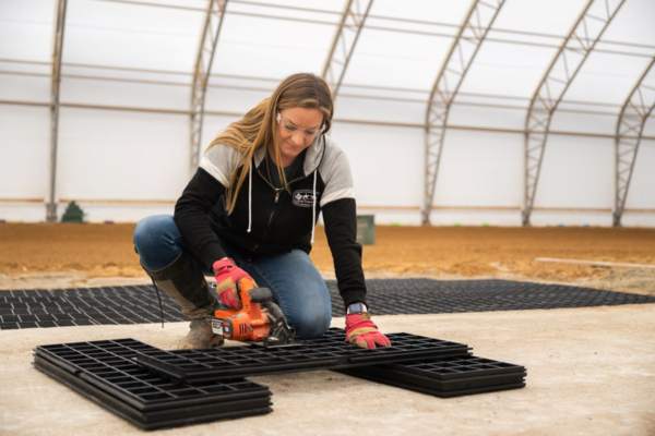 woman cutting horse stall floor panels with power saw
